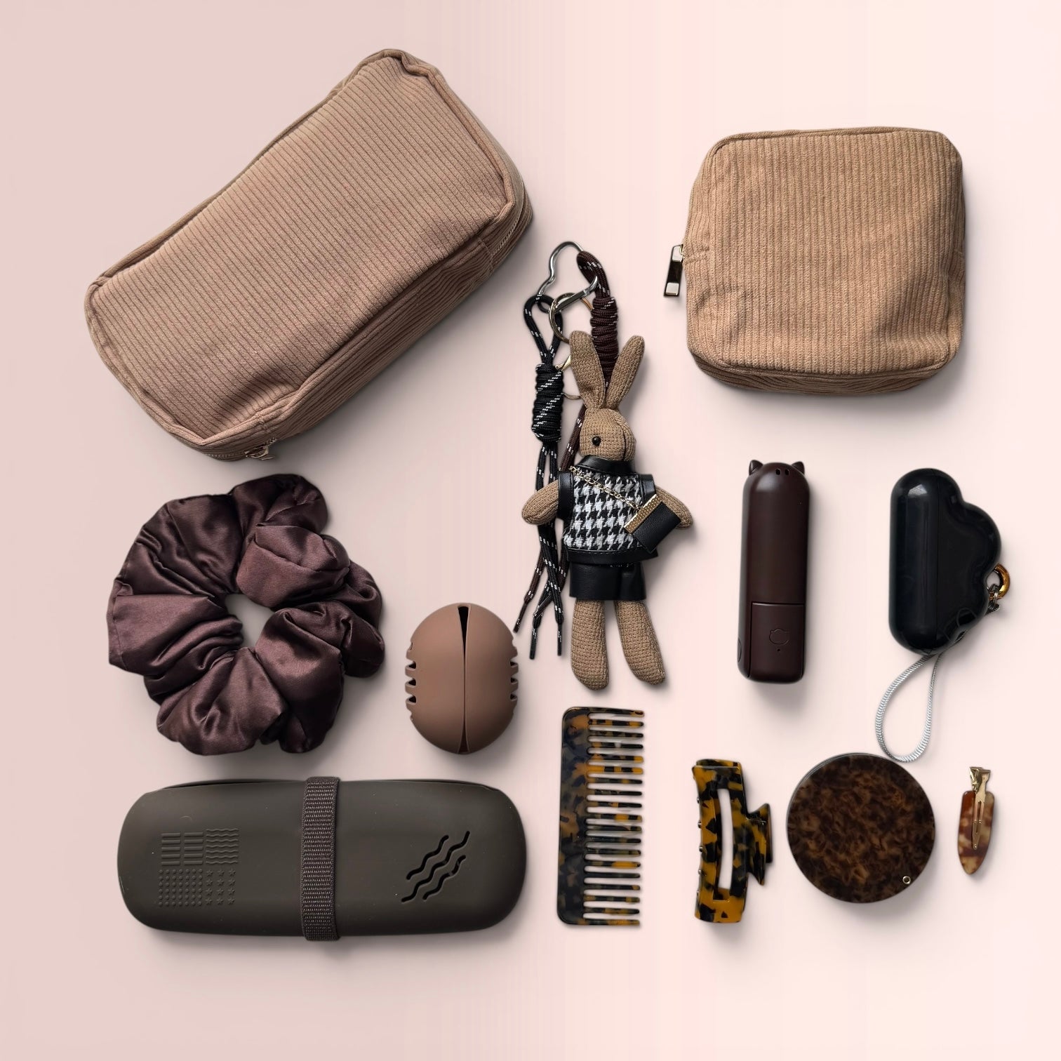 Flatlay of the Ultimate Mocha 11-Piece Purse Organizer Kit featuring corduroy pouches, silicone brush case, mini fan, and tortoise-shell hair accessories on a soft pink background.